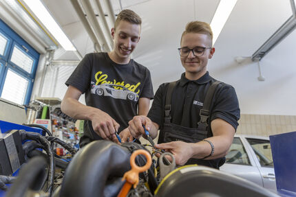 Zwei lachende Gesellen beim Motormanagement.