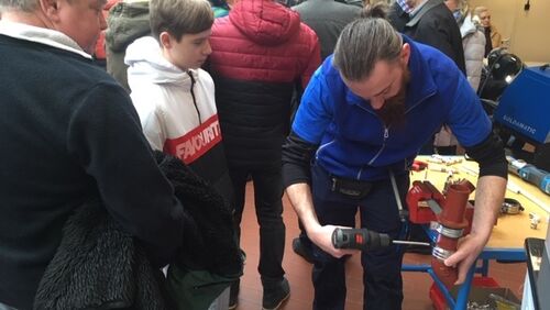 Besucher beimTtag der Bildung sehen sich an wie Klempnerarbeiten ausgeführt werden 