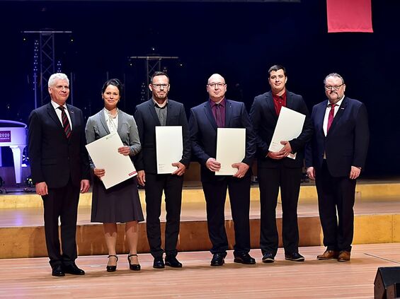 Vier Betriebswirte mit ihren Urkunden auf der Bühne.